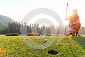 Asian Woman golf player crouching and study the green before putting shot.