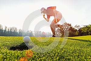 Asian woman golfer action to win after long putting golf ball on the green golf, sunset time,