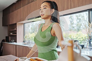 Asian woman in green, breakfast time, sunny kitchen