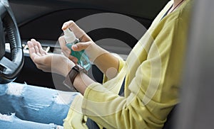 Asian woman in green shirt using alcohol spray washing and cleaning her hands for prevent Covid-19 or Coronavirus before driving a