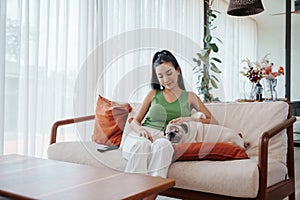 Asian Woman in Green sleeveless Relaxing on Beige Sofa with Pug