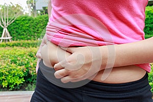 Asian woman hand holding belly fat in the park