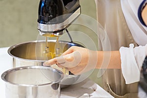 Asian woman hand is holding a bowl and egg beater flour mixer on