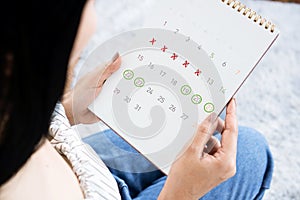 Asian woman hand holding calendar  counting the date and checking her menstrual cycle planning for ovulation