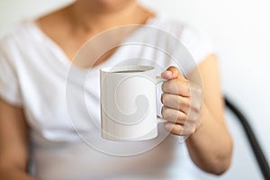 Asian woman hand holding a white cup of mug of hot black Americano coffee