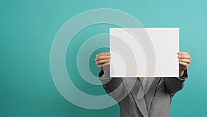 Asian woman hands holding blank paper board and wear grey suit isolated on blue or green mint background