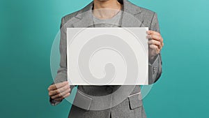 Asian woman hands holding blank paper board and wear grey suit isolated on blue or green mint background