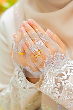 Asian woman hands painted with henna making dua