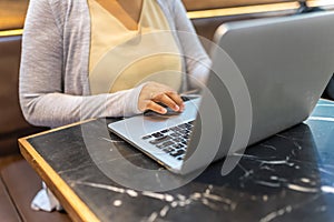 Asian woman hands using laptop touchpad on coffee table