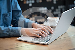 Asian woman hands using laptops on table at cafe