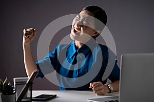 Asian woman happy in blue shirt make winning gesture working on a laptop at office.  on white background