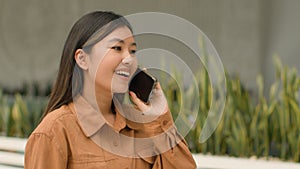 Asian woman happy customer client walk in shopping mall talk phone answer mobile call speak carefree chinese japanese