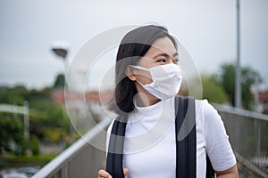 Asian woman happy smiling wearing protective face mask walking on overcrossing city street. New lifestyle with Corona Virus COVID-