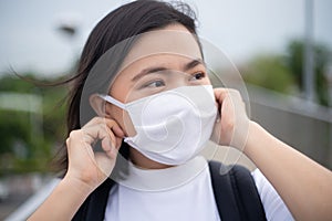 Asian woman happy smiling wearing protective face mask walking on overcrossing city street. New lifestyle with Corona Virus COVID-