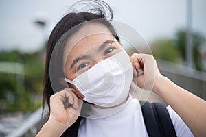 Asian woman happy smiling wearing protective face mask walking on overcrossing city street. New lifestyle with Corona Virus COVID-