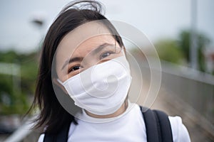 Asian woman happy smiling wearing protective face mask walking on overcrossing city street. New lifestyle with Corona Virus COVID-