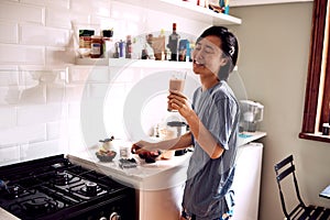 Asian woman, happy and smoothie in kitchen for healthy breakfast, morning routine and body detox in pajamas. Person