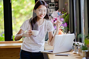 Asian woman or a happy student smiles on a desk with a computer