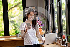 Asian woman or a happy student smiles on a desk with a computer