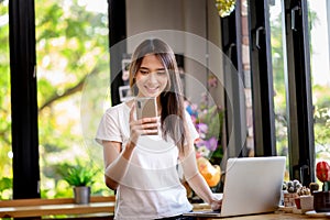 Asian woman or a happy student smiles on a desk with a computer