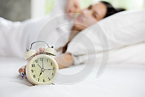 Asian woman happy wake up and turning off the alarm clock having