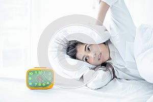Asian woman happy waking up and turning off the alarm clock having a good day