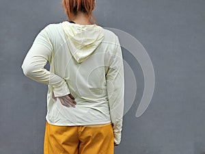 Asian woman has lower back pain, Standing on isolated gray background