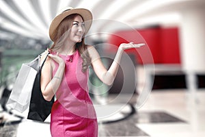 Asian woman in hat holding shopping bags in the mall