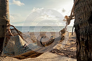 Asian woman with hat relaxing relaxing in a hammock between palm trees, Summer happy beach vacation concept