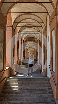 Asian woman in hat and sneakers standing in the middle of a stairway in a portico