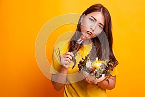 Asian woman hate salad in yellow dress