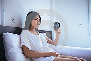 Asian woman hates getting stressed waking up early,Female stretching her hand to ringing alarm to turn off alarm clock