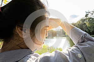 Asian woman have conjunctivitis,cataract,young female covering face by hand of bright sun in outdoor on sunny day,feel dizzy,risk photo