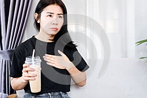 Asian woman have problem with heart beats faster after drinking coffee, heart palpitations caused by caffeine concept