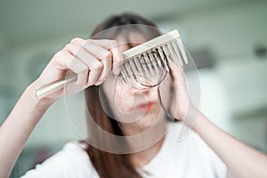 Asian woman have problem with long hair loss attach to comb brush