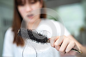 Asian woman have problem with long hair loss attach to comb brush