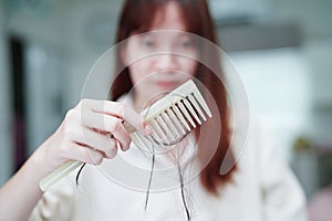 Asian woman have problem with long hair loss attach to comb brush