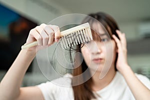 Asian woman have problem with long hair loss attach to comb brush