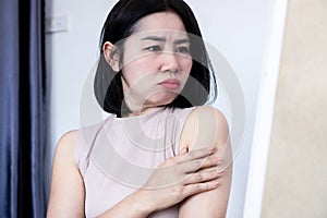 Asian woman have problem with upper arm fat checking extra skin in a mirror