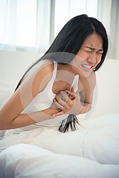 Asian woman having heart attack on her bed.