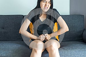 Asian woman having painful stomachache on sofa after wake up,Female suffering from abdominal pain period cramps