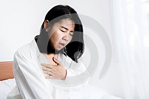 Asian woman having panic disorder in bed hand holding her chest difficult to breath