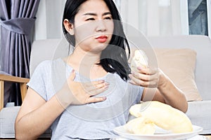 Asian woman having a problem with heartburn after eating too much durian hand holding her chest pain