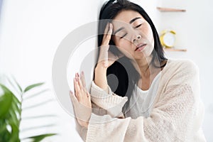 Asian woman having problem with Meniere`s disease, fainting or dizziness hand holding her head leaning against the wall