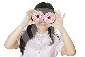 Asian woman having some fun with delicious strawberry frosted donuts