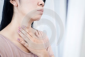 Asian woman having sore throat, hand touching neck feeling pain from inflammation