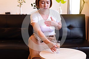 Asian woman having or symptomatic reflux acids,Gastroesophageal reflux disease,Drinking water