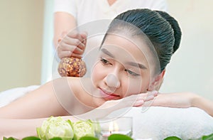Asian woman having Thai herbal compress massage in spa env