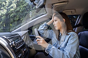 Asian woman with headache in a car