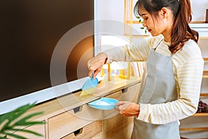 Asian woman with headache doing spring cleaning chores in her living room at home overworked housekeeping service